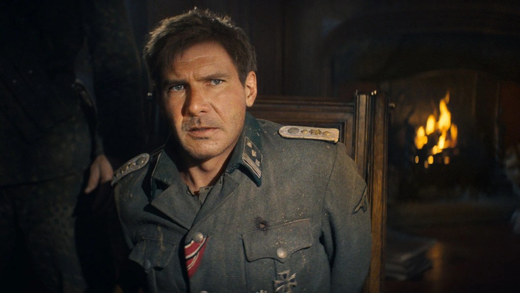 A still from Indiana Jones and the Dial of Destiny (James Mangold, 2023), showing actor Harrison Ford disguised as a German officer during World War Two. Ford's face has been digitally retouched to appear younger than the 80-year-old actor actually does today.